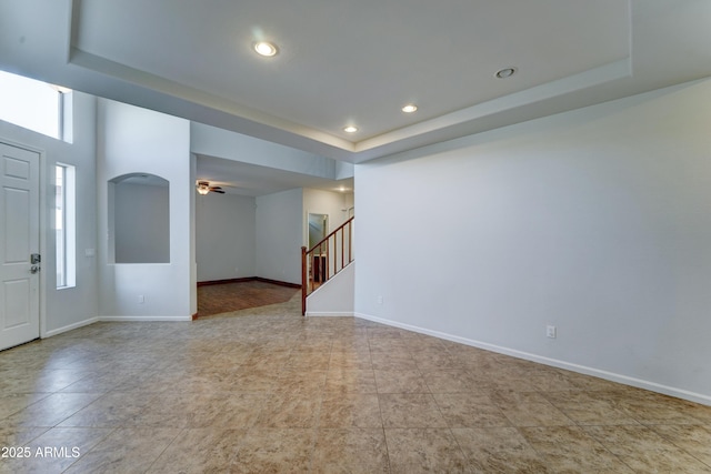 interior space featuring recessed lighting, a tray ceiling, baseboards, and stairs