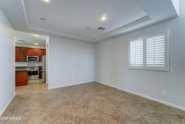 unfurnished living room featuring a tray ceiling, baseboards, and visible vents