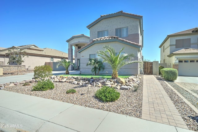 view of front facade with stucco siding, fence, a tile roof, and a gate