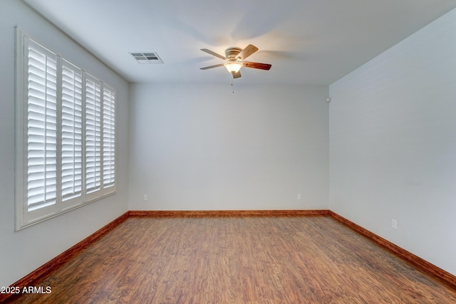 spare room featuring visible vents, baseboards, ceiling fan, and wood finished floors