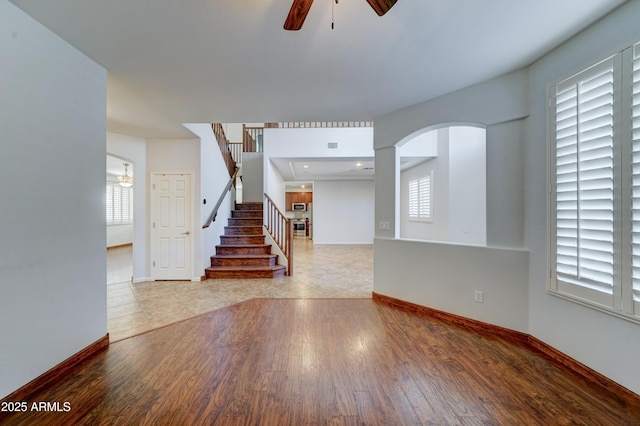 interior space with visible vents, a ceiling fan, wood finished floors, stairway, and baseboards