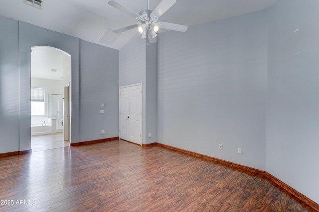 unfurnished room featuring baseboards, ceiling fan, wood finished floors, arched walkways, and high vaulted ceiling