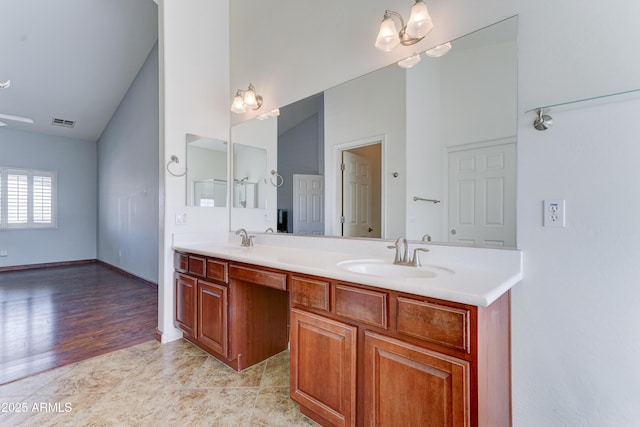 bathroom featuring a sink, visible vents, lofted ceiling, and double vanity