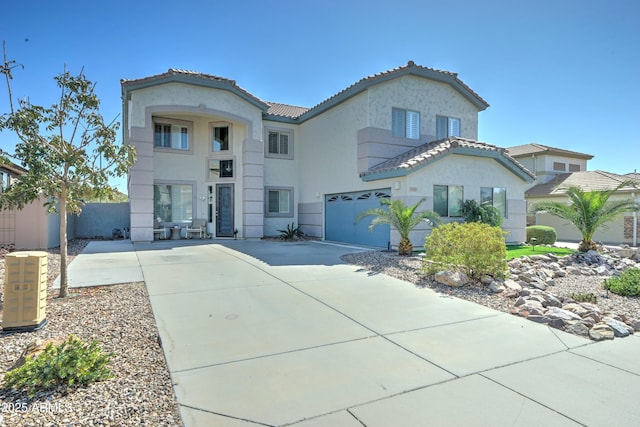 mediterranean / spanish-style home with stucco siding, fence, concrete driveway, and a tiled roof