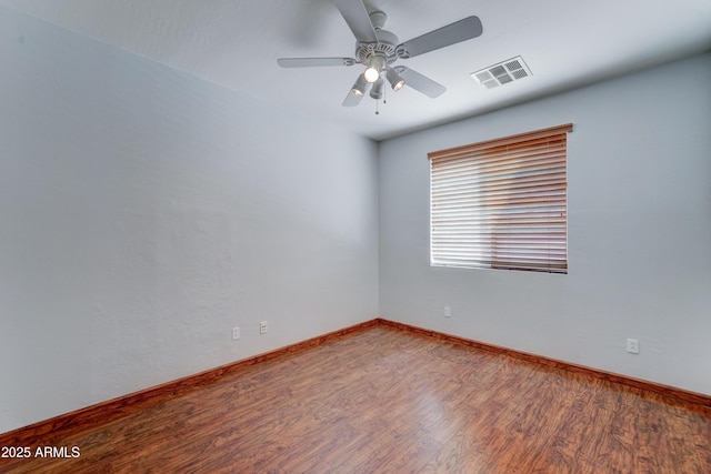 empty room with ceiling fan, visible vents, baseboards, and wood finished floors