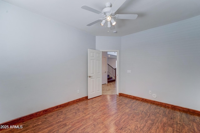 spare room with baseboards, stairway, a ceiling fan, and light wood-style floors