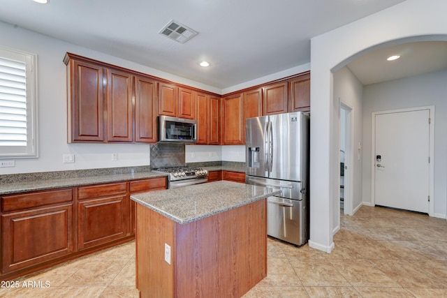 kitchen featuring visible vents, a kitchen island, recessed lighting, arched walkways, and stainless steel appliances