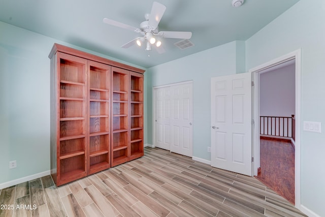 unfurnished bedroom featuring visible vents, ceiling fan, baseboards, light wood-type flooring, and a closet