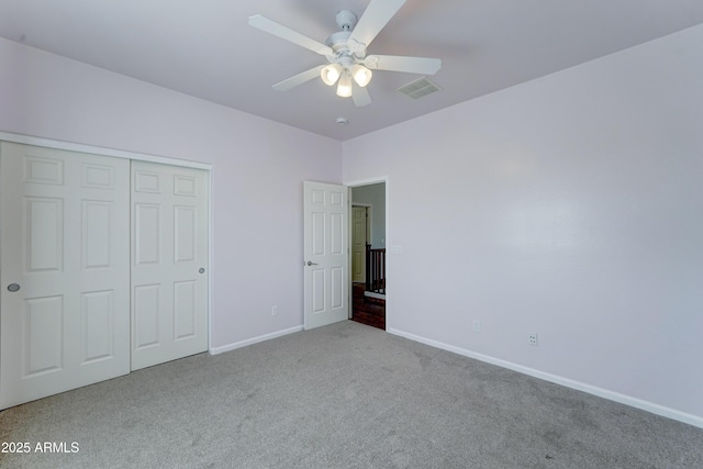 unfurnished bedroom featuring carpet, visible vents, baseboards, ceiling fan, and a closet