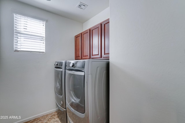 clothes washing area featuring washer and clothes dryer, visible vents, cabinet space, and baseboards