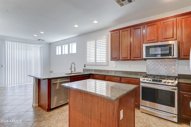 kitchen featuring visible vents, a center island, appliances with stainless steel finishes, a peninsula, and a sink