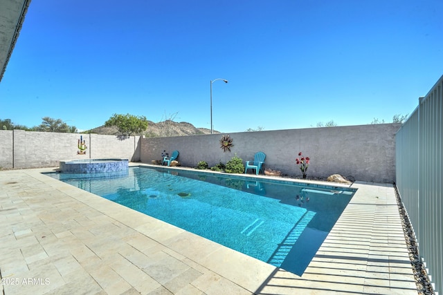 view of pool with a patio area, a pool with connected hot tub, and a fenced backyard