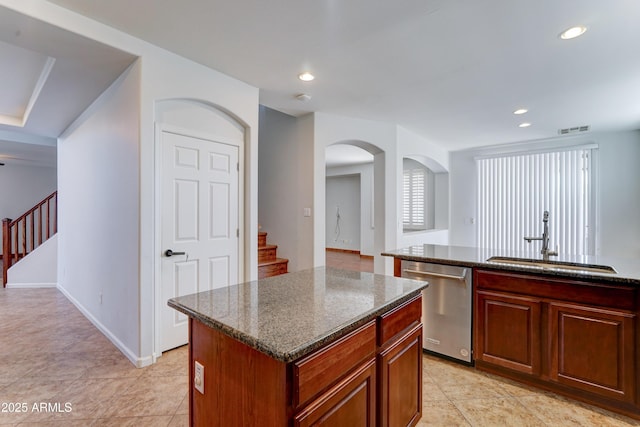 kitchen featuring dark stone countertops, a kitchen island, recessed lighting, a sink, and dishwasher