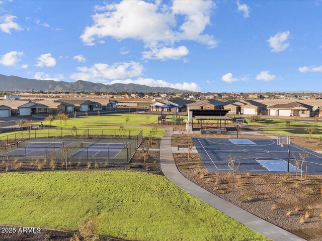 exterior space featuring a residential view, fence, a yard, community basketball court, and a mountain view