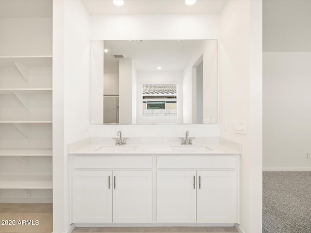 bathroom with double vanity, visible vents, a sink, and recessed lighting