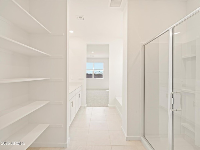 bathroom with tile patterned flooring, visible vents, vanity, a bath, and a stall shower