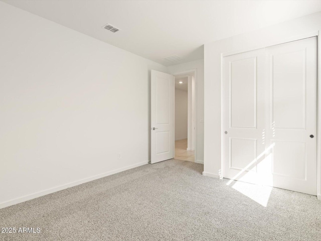 unfurnished bedroom with carpet, a closet, visible vents, and baseboards