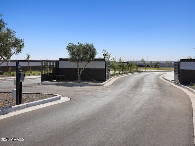 view of road with a gate, a gated entry, and curbs