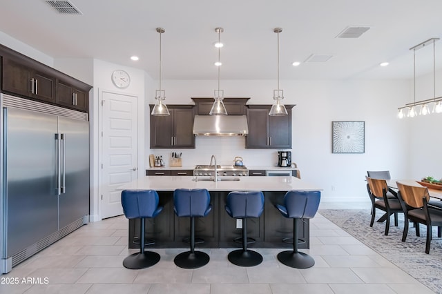 2513 E Pleasant Ln, Phoenix, AZ 85042 - kitchen with stainless steel built in refrigerator, wall chimney range hood, light countertops, dark brown cabinetry, and recessed lighting