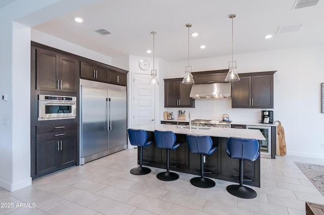 2513 E Pleasant Ln, Phoenix, AZ 85042 - kitchen with stainless steel appliances, wine cooler, a sink, dark brown cabinets, and ventilation hood