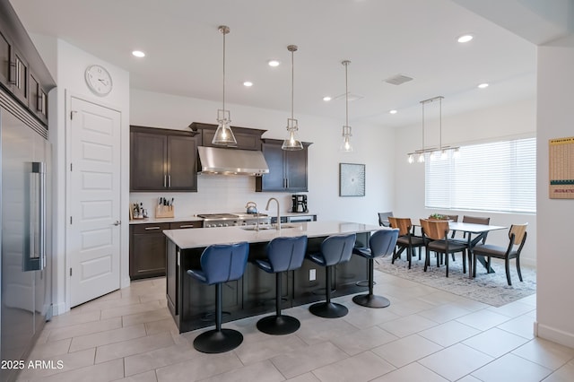 2513 E Pleasant Ln, Phoenix, AZ 85042 - kitchen with built in refrigerator, under cabinet range hood, light countertops, decorative backsplash, and a kitchen island with sink
