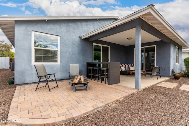 rear view of property featuring central AC unit, an outdoor fire pit, and a patio