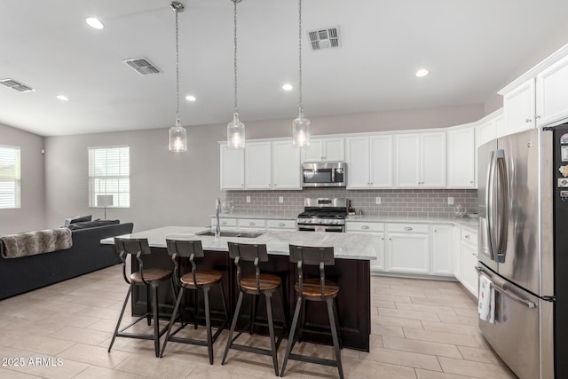 kitchen with white cabinetry, stainless steel appliances, and a center island with sink