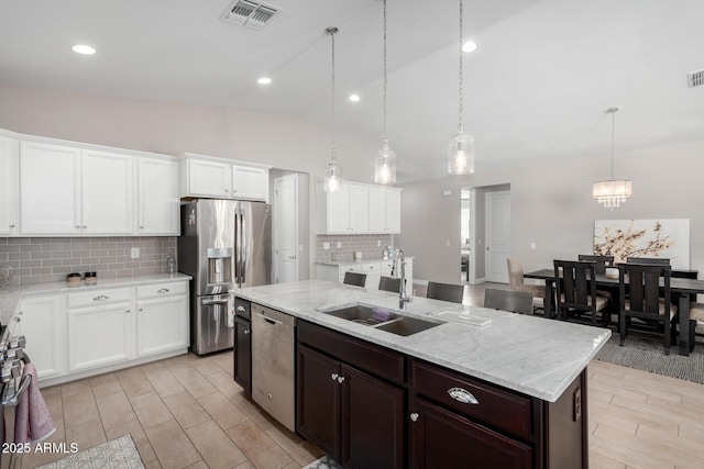 kitchen featuring tasteful backsplash, sink, hanging light fixtures, a kitchen island with sink, and appliances with stainless steel finishes