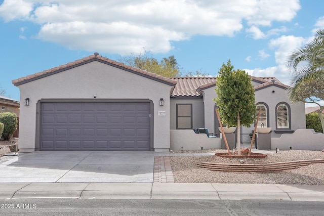 mediterranean / spanish-style home with stucco siding, driveway, a tile roof, and an attached garage