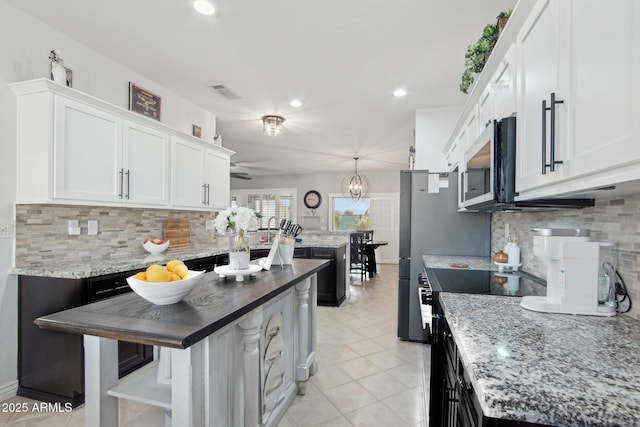 kitchen with visible vents, stainless steel microwave, range with electric stovetop, white cabinets, and light tile patterned floors