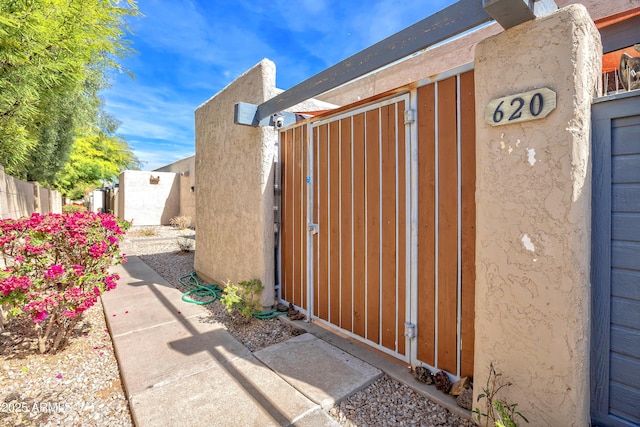 view of property exterior with a gate, fence, and stucco siding