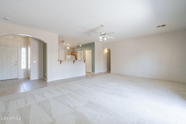 unfurnished living room featuring ceiling fan and light carpet