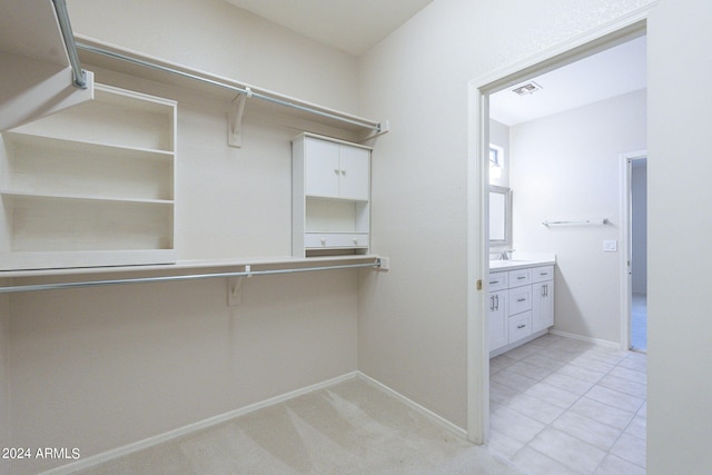 spacious closet with light colored carpet and sink