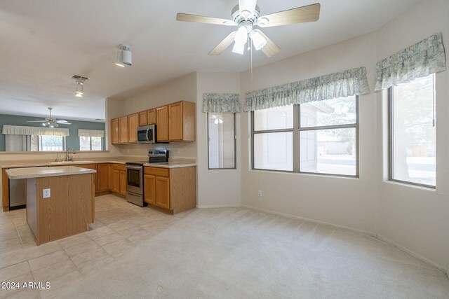 kitchen with a kitchen island, light carpet, stainless steel appliances, kitchen peninsula, and ceiling fan