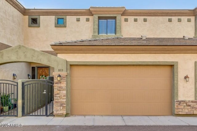 3820 E Mcdowell Rd Unit 102, Phoenix, AZ 85008 - view of front of property with stucco siding, an attached garage, a gate, and stone siding