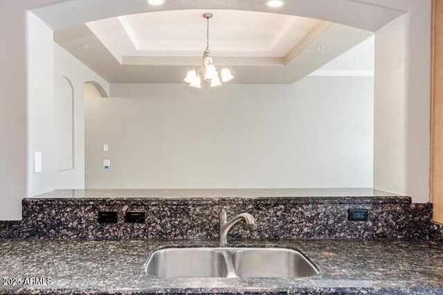 3820 E Mcdowell Rd Unit 102, Phoenix, AZ 85008 - kitchen featuring a raised ceiling, a sink, arched walkways, dark stone counters, and a chandelier