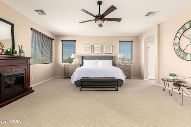 bedroom with baseboards, visible vents, carpet flooring, and a glass covered fireplace
