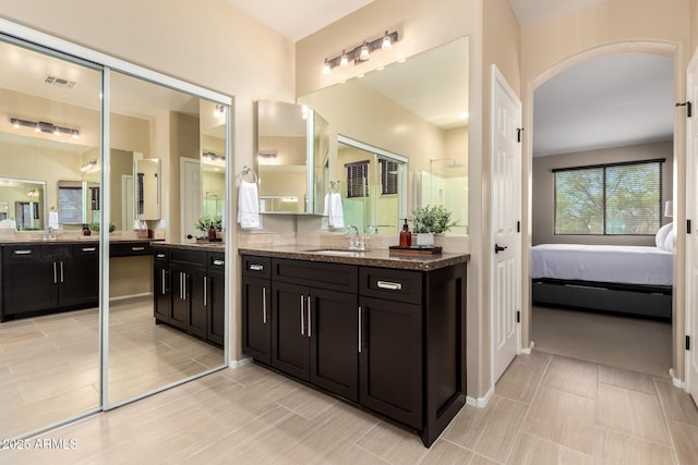ensuite bathroom with visible vents, two vanities, ensuite bathroom, and a sink