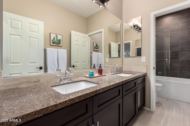 bathroom with toilet, double vanity, a sink, and bathtub / shower combination