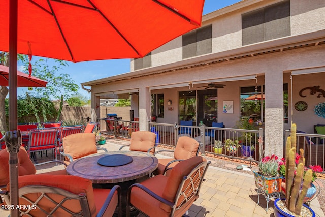view of patio with fence, outdoor dining area, and a ceiling fan