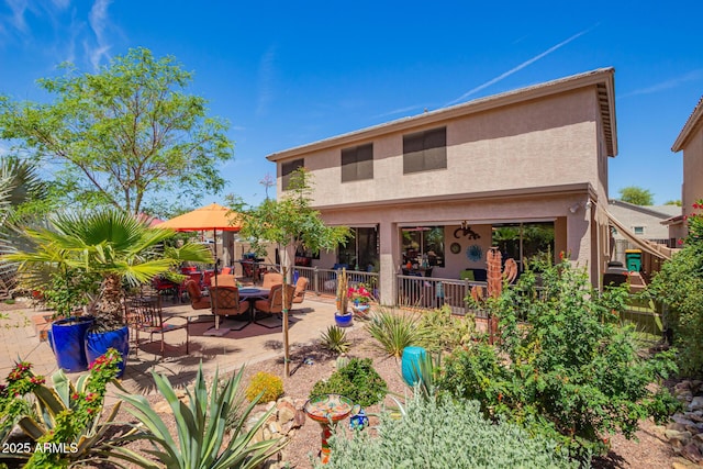 rear view of house featuring stucco siding and a patio area