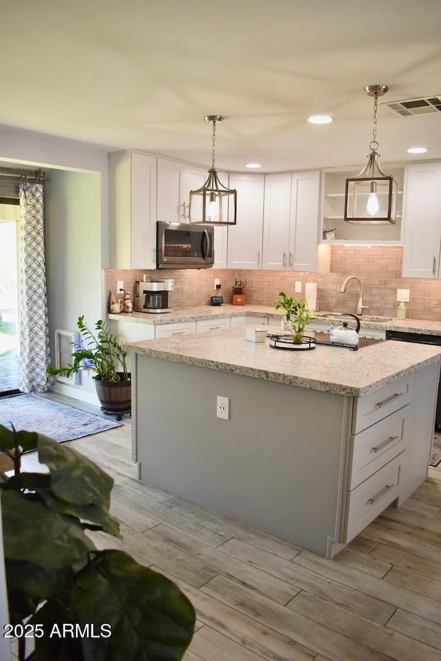 4755 E Gary St, Mesa, AZ 85205 - kitchen with stainless steel microwave, a center island, white cabinets, tasteful backsplash, and hanging light fixtures