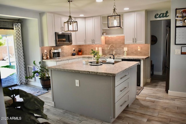 4755 E Gary St, Mesa, AZ 85205 - kitchen featuring stainless steel microwave, light wood finished floors, a kitchen island, backsplash, and recessed lighting