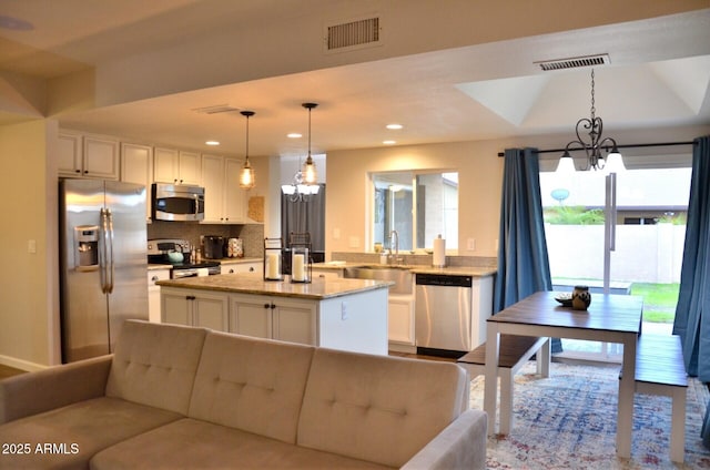 kitchen featuring a center island, visible vents, a sink, white cabinets, and appliances with stainless steel finishes