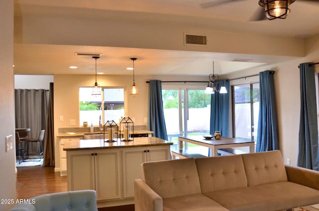 kitchen featuring dark wood-style flooring, a center island, visible vents, and a sink