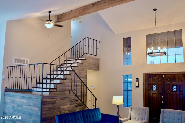 foyer featuring ceiling fan with notable chandelier, high vaulted ceiling, visible vents, stairway, and beamed ceiling