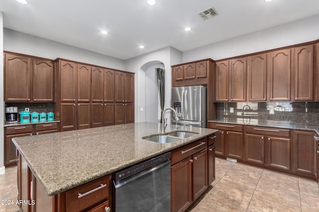 kitchen featuring a center island with sink, sink, appliances with stainless steel finishes, light stone countertops, and backsplash