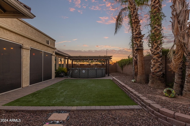 yard at dusk featuring a patio and a hot tub