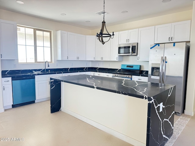 kitchen featuring visible vents, a sink, appliances with stainless steel finishes, pendant lighting, and a center island