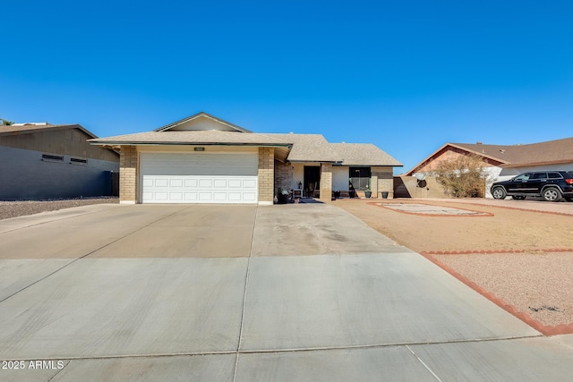 ranch-style house with a garage, a shingled roof, concrete driveway, and brick siding